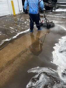 Blog 12 After: A Worker Uses A Surface Cleaner Machine To Pressure Wash A Dirty Concrete Ground.